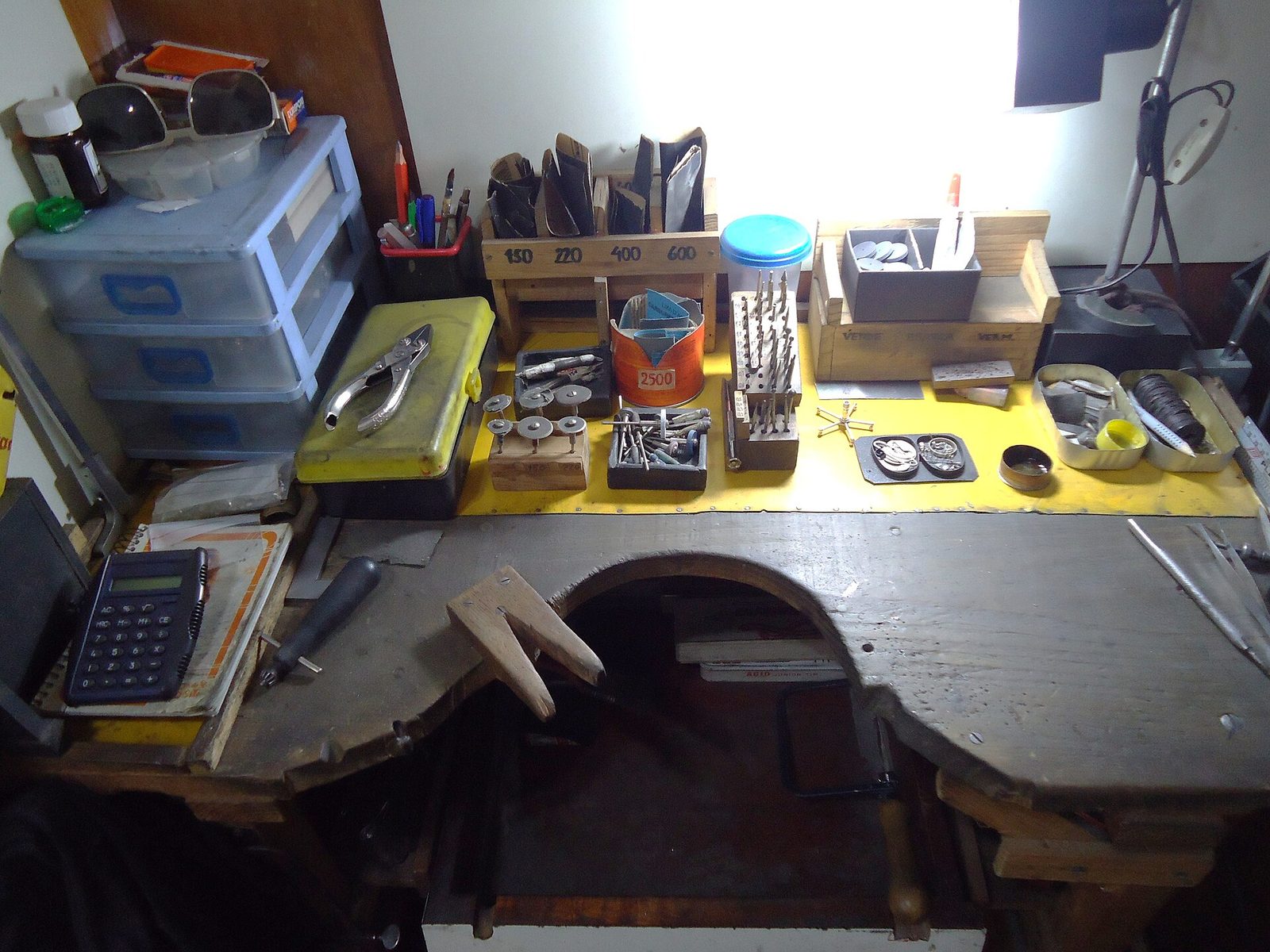 A jeweler's workbench with a bench lamp, polishing tools and grit sticks laid out, the kind of workspace a memo stone gets fitted and shown from.