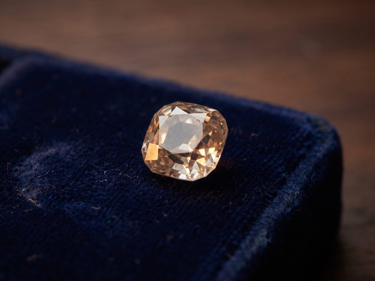 A single warm-toned old mine cut resting on navy velvet, its small table and chunky facets catching the light