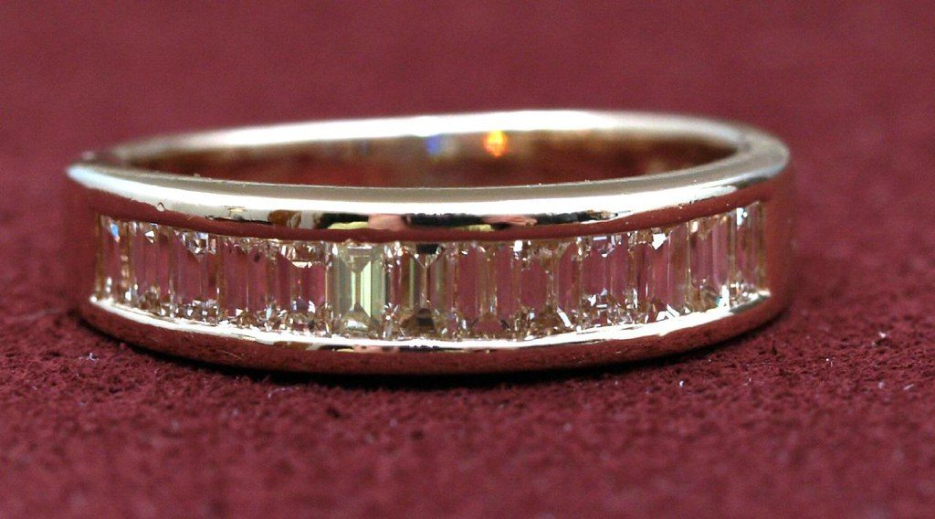 Rectangular baguette-cut diamonds channel-set edge to edge around a gold ring band